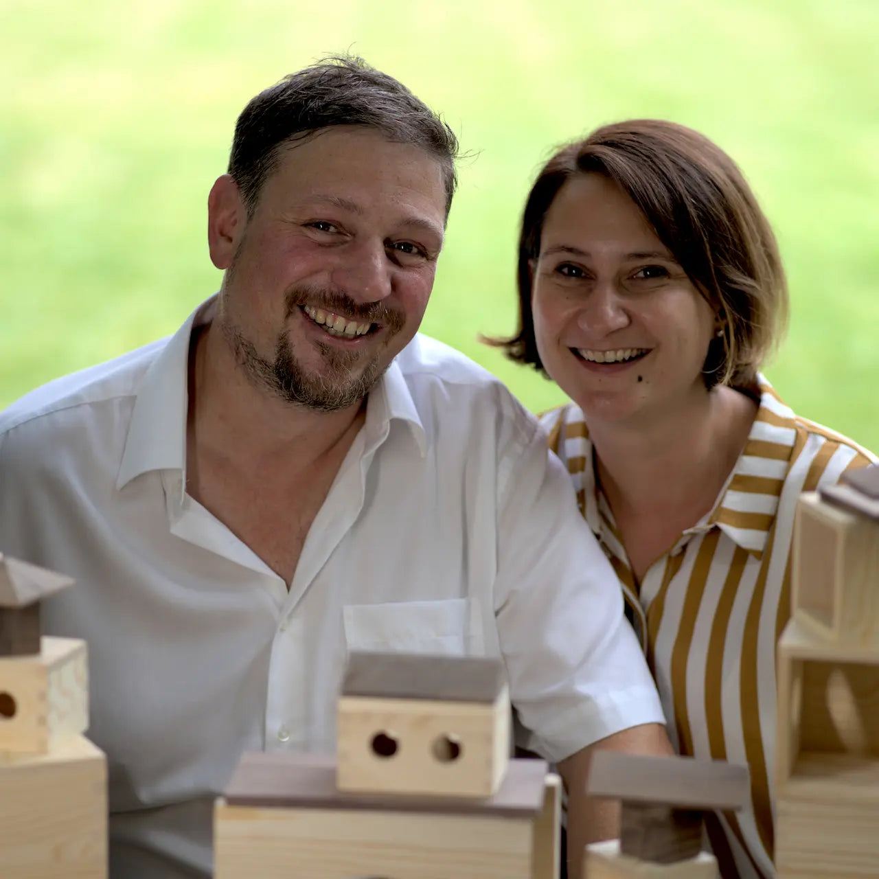 Foto der beiden Matzbox Gründer - Die Architekten Katharina und Christoph Matz sitzen hinter ein paar Türmen aus Holzbausteinen der Matzbox