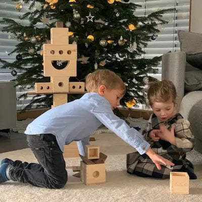 2 Kinder spiel mit der Matzbox vor einem Weihnachtsbaum